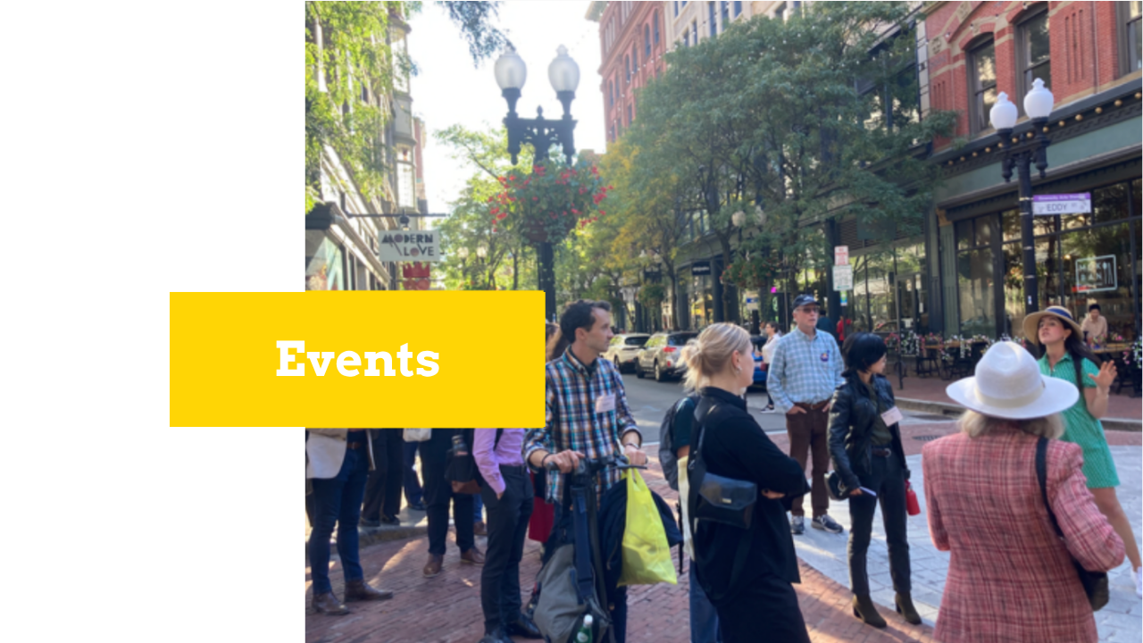Group of people standing on Westminster Street in Providence, RI. There is a woman in a green dress and sun hat giving a tour to the rest of the group. There is a yellow text box with white text that reads "Events."