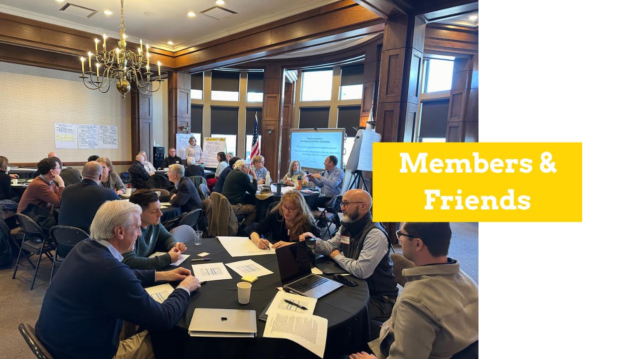 Image of a room full of people seated at round tables writing on post it notes. There is a yellow text box with white text that reads "Members & Friends."