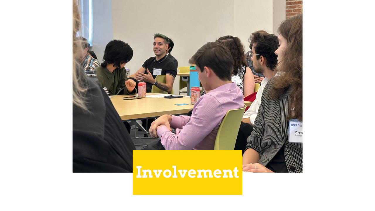 Image of a group of nine people at a table. One man in a black t-shirt is speaking. There is a yellow text box with white text that reads "Involvement."
