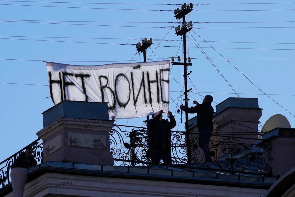  Original caption: Men take down a sign with writing reading "No War" which was hanging over Nevsky prospect, the central avenue of St. Petersburg, Russia, Tuesday, March. 1, 2022. [ Article. ]  DMITRI LOVETSKY, AP  