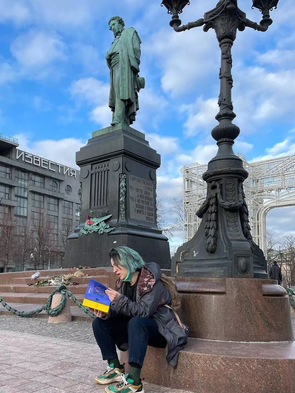  Original caption: Yulia Zhivtsova sits in Pushkin Square holding Harry Potter books with the colors of the Ukrainian flag. Zhivtsova has been participating in the protests against Russia's invasion of Ukraine. [ Article. ]   Yulia Zhivtsova via NPR 