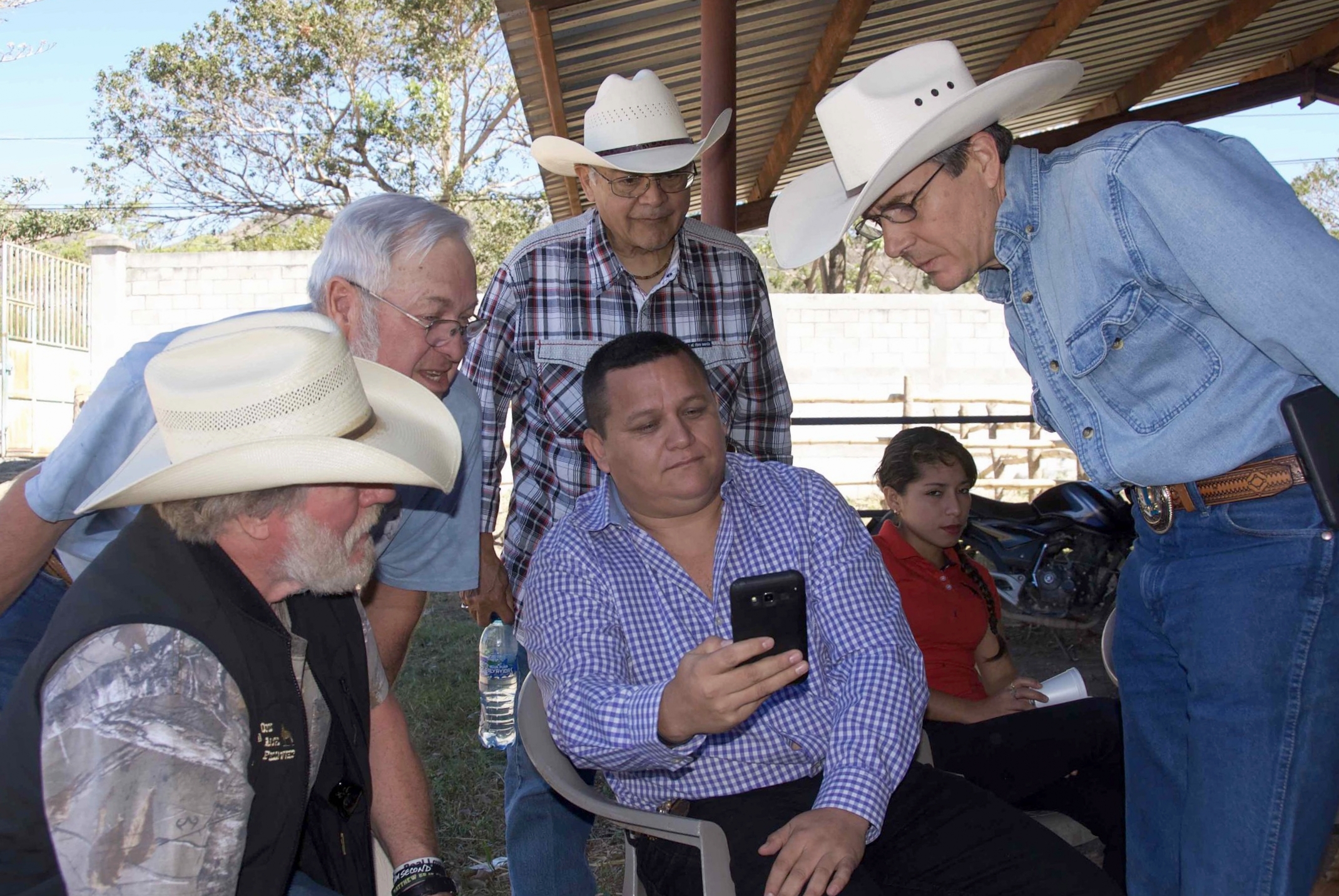 US cowboys enjoy seeing personal horse photos on the phone of a Guatemalan cowboy (and town lawyer) before a dairy co-op tour and lunch meeting with a womens' group.