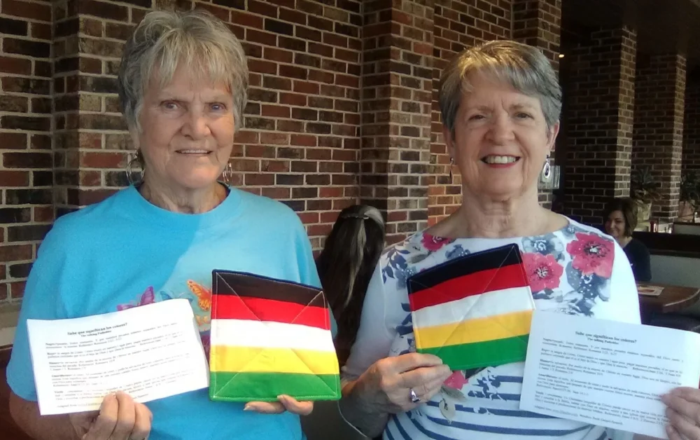 Janice Brite and Virginia Jones hold up two of the 135 "talking" potholders they made for our ladies mission team to use in Guatemala in January 2018. The colors help people share the gospel, and the sheets are the printed Spanish version of the message. 