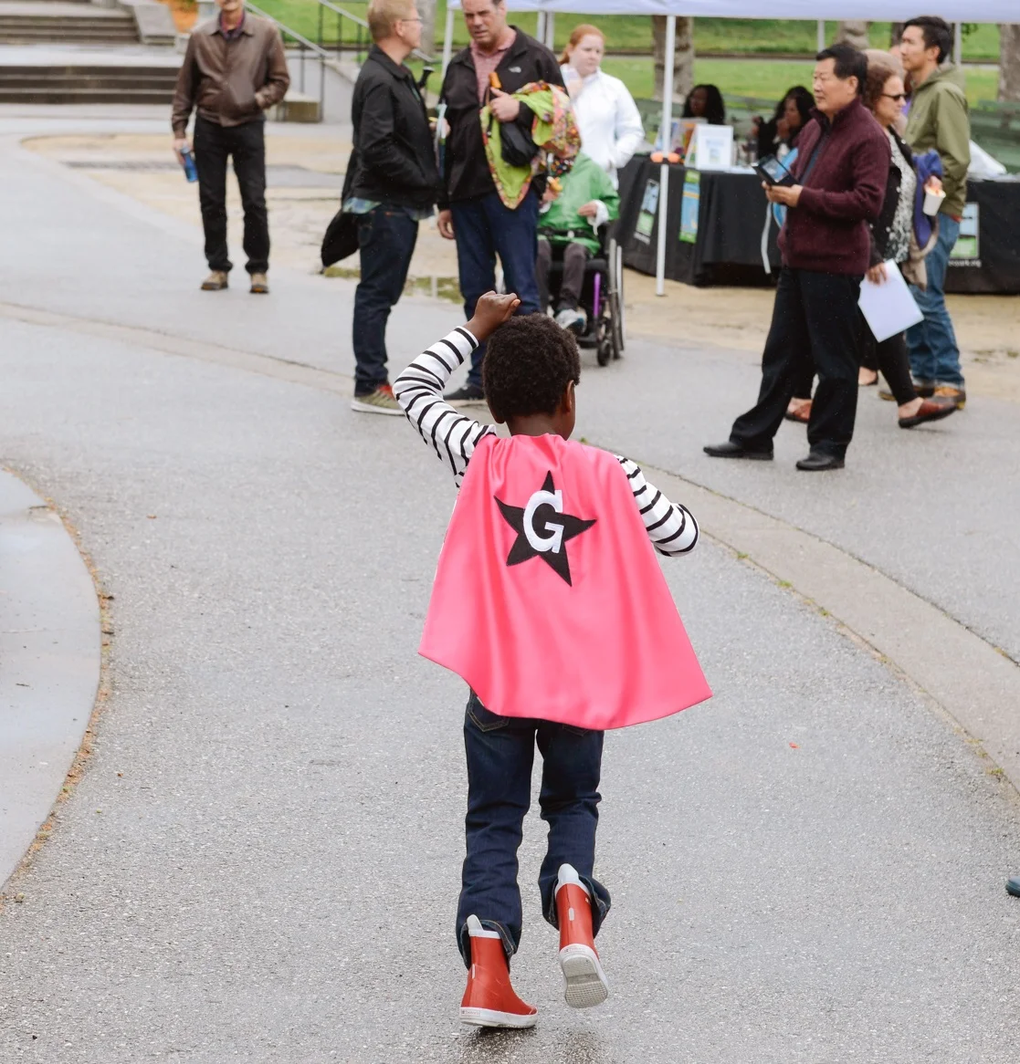 Girl running through Golden Gate Park in a pink cape