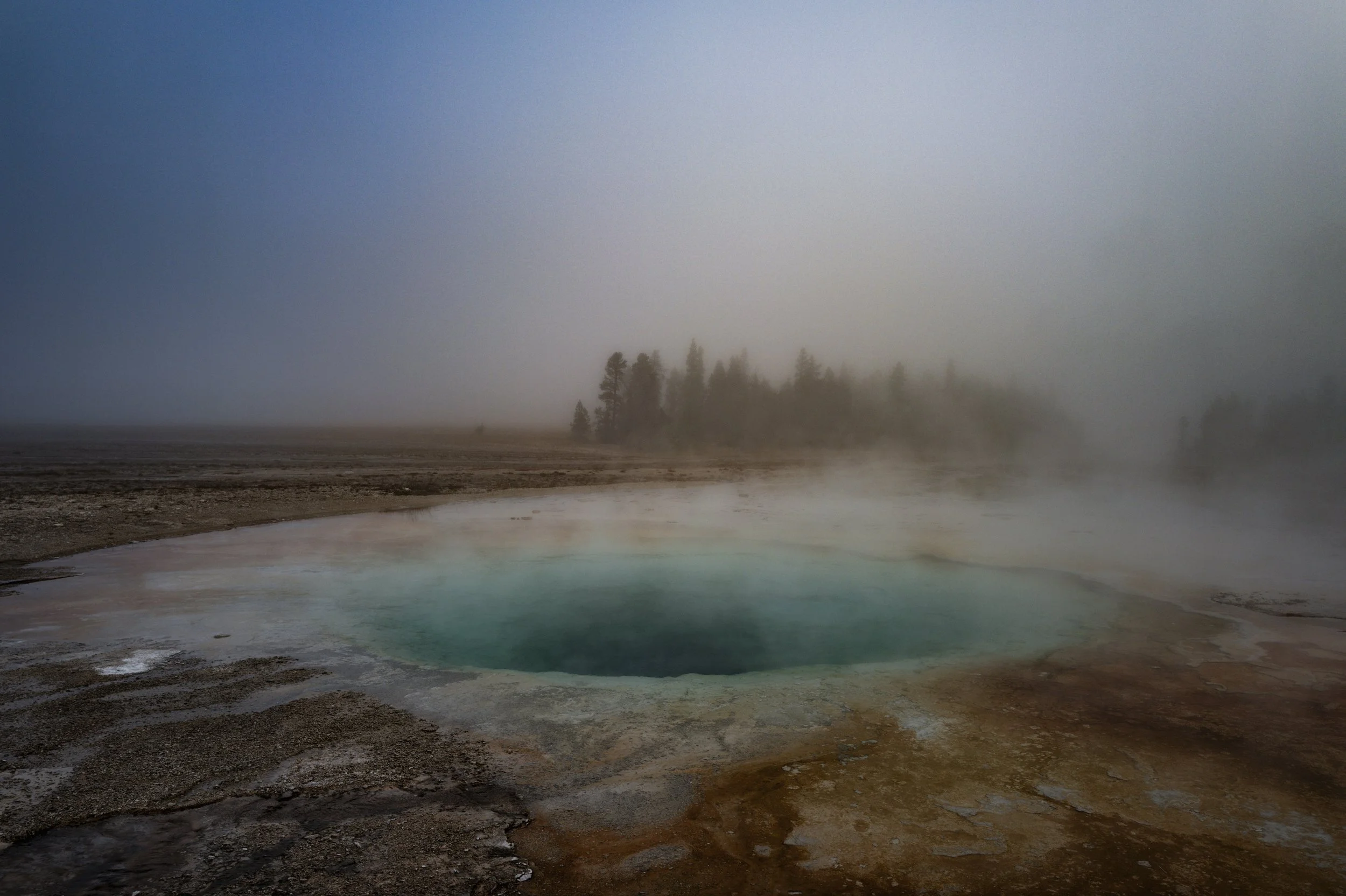 A world veiled in steam and shadow. This series captures the quiet, powerful beauty of Yellowstone's geysers and hot springs at dawn, where dense fog and geothermal steam obscure the rising sun. The resulting images present a moody, timeless landsca