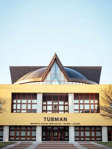 Tubman Museum of African American Art , Matthew Smith, 2015 Completed in 2015, the Tubman Museum is a beautiful 49,000 square foot building featuring African American art, history and culture. The geometric symmetry of the structure is unmistakable and extraordinary. The pointed roof architecture looks as though it is piercing the crystal clear sky, creating significant contrast and negative space.