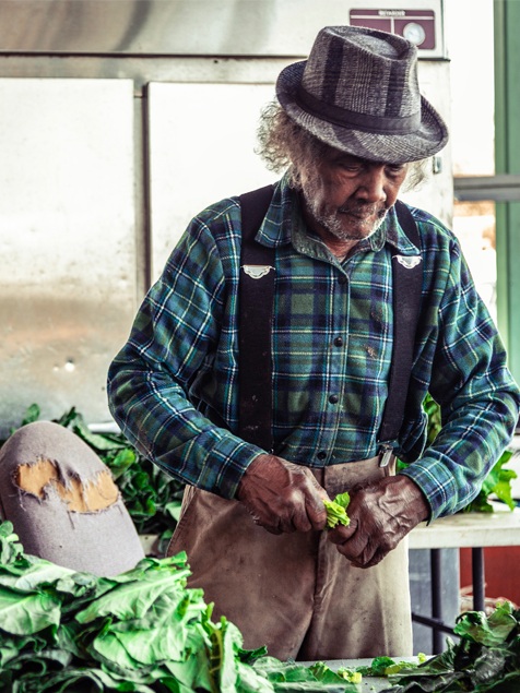 Green Pickin’ Marvin , Sydney A. Foster, 2019 ”Marvin Jones has been picking greens all his life, at least that is what he told me. I was infatuated with how fast he was able to pick the greens of stem. He was a machine. Marvin said to me, ‘Baby, you trying to turn me in and spy on me?’ I looked up from behind my camera and he said, “I’m just playing, take whatever pictures you need.” I met Marvin while roaming around at the State Farmers Market in Macon, Georgia. He had 2 of his grand daughters with him.” -S.A.F.