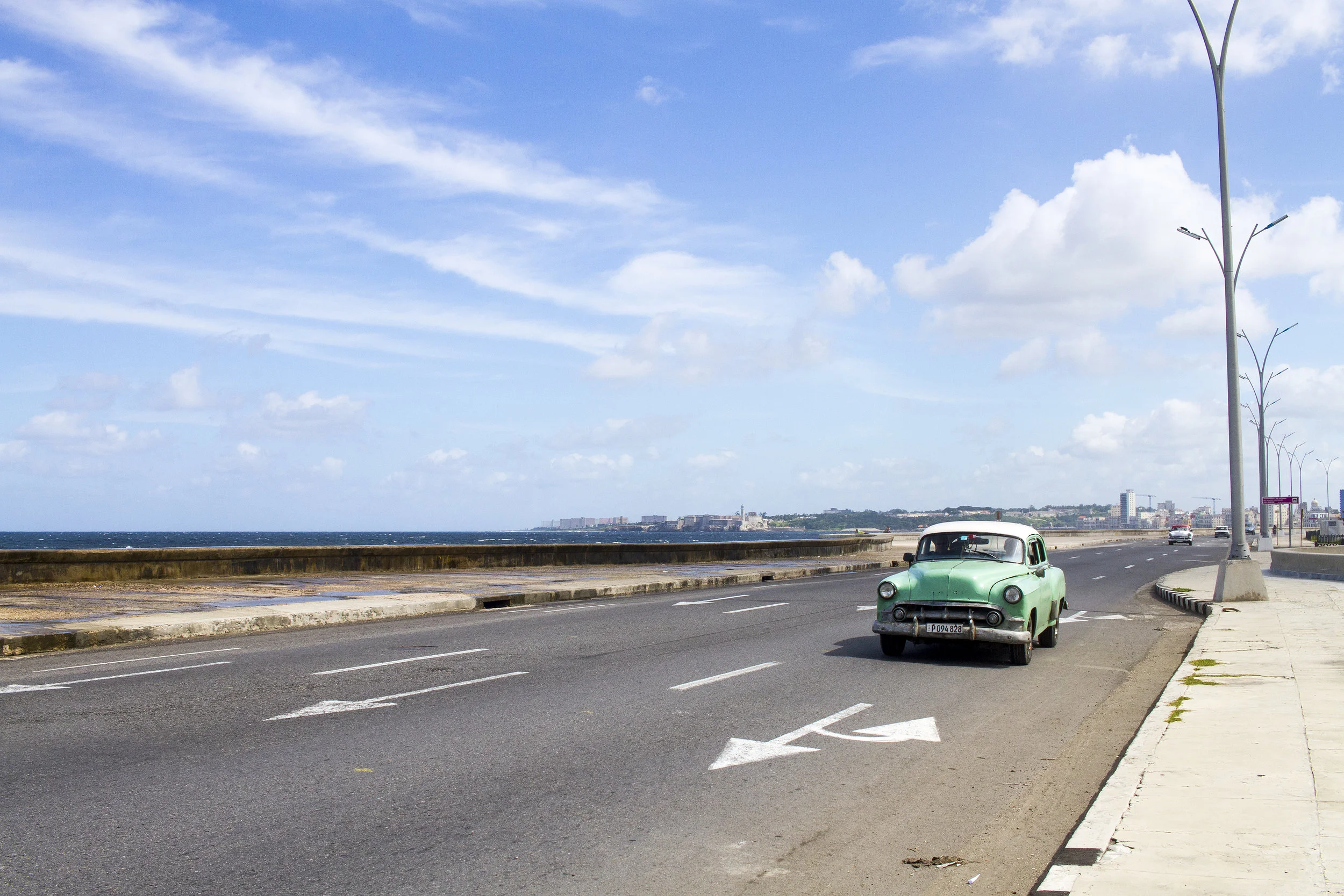 A restored classic car driving down the Malecón in La Habana
