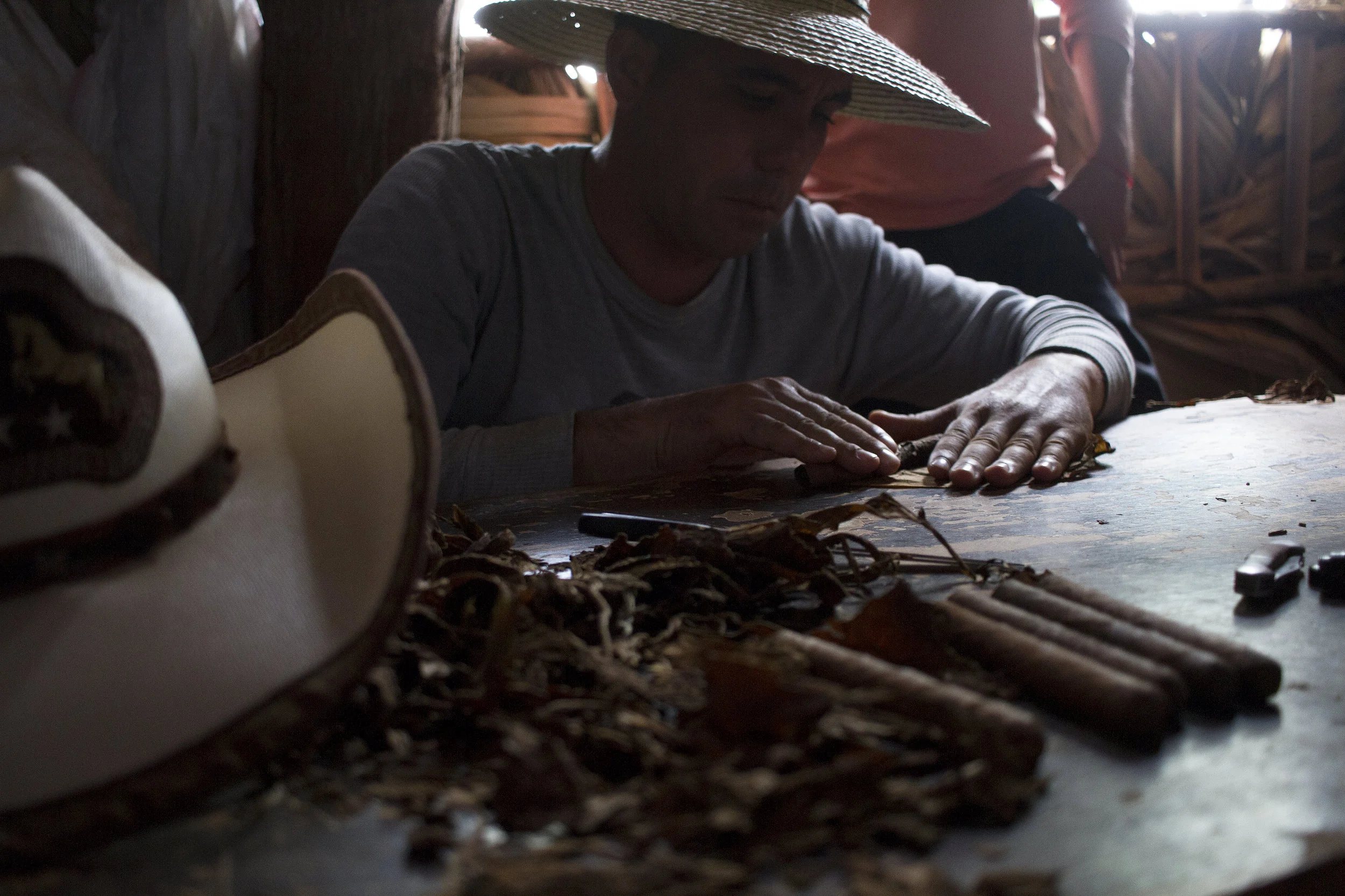 A tobacco farmer rolls a cigar in his dry house