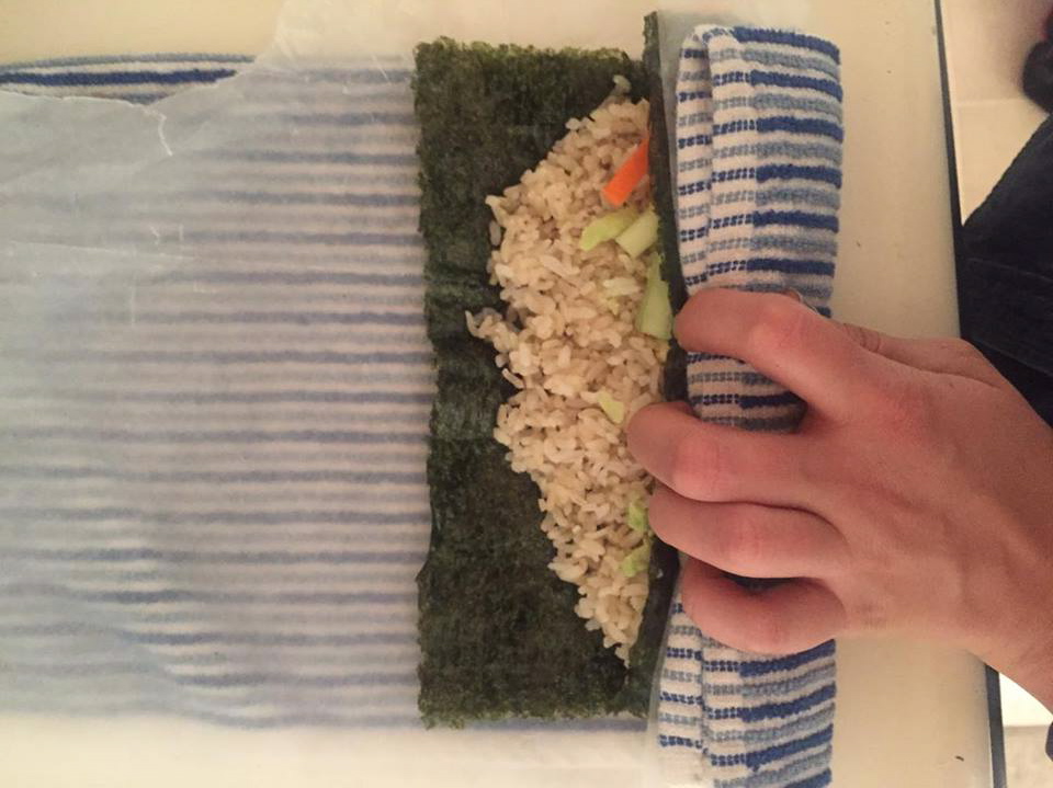 STEP 3: Line the towel, wax paper, and Nori sheet up and using the towel begin to roll everything together and push down tightly. 