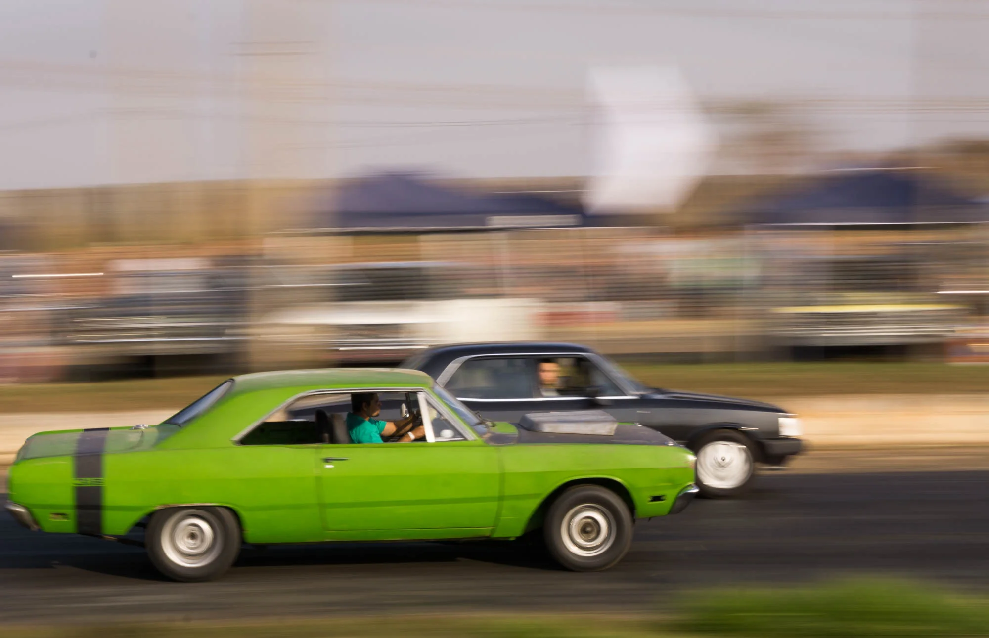 Green and Black car racing down track