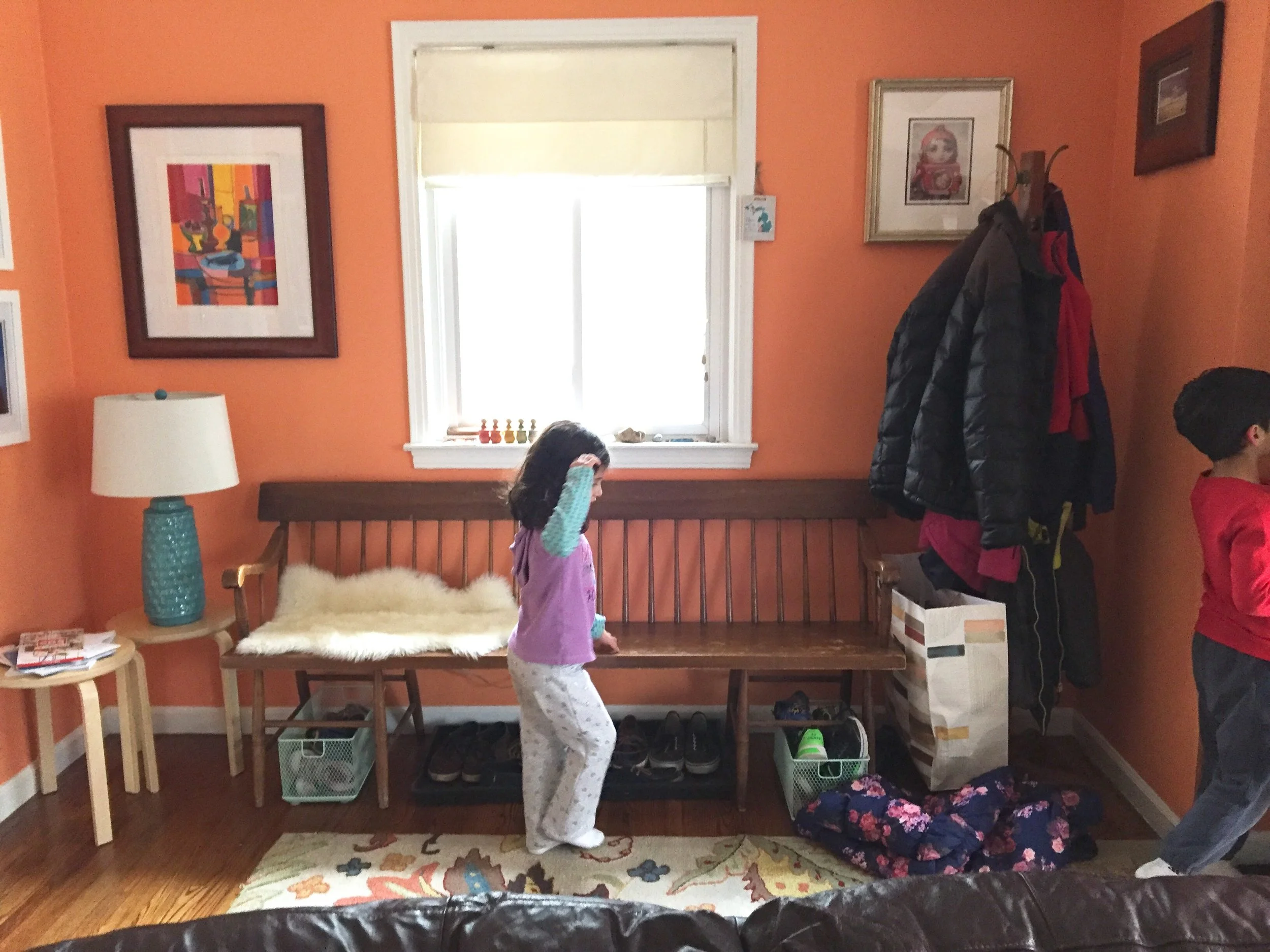 Meena throws her coat on the floor. I say, "Please hang up your coat on the rack". Meena looks at it.