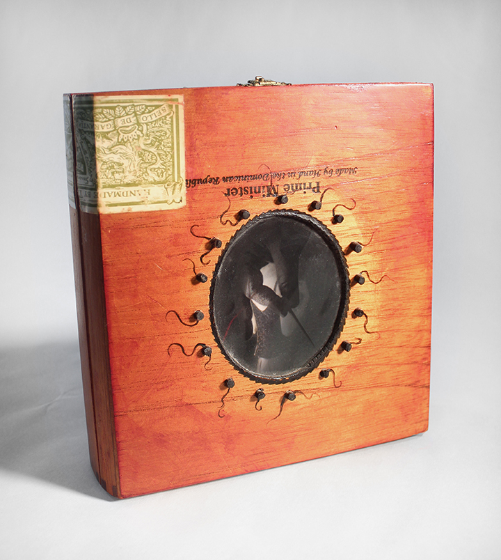 The outside of the box has a window cut in it. There is a piece of Ortho Lith film in the window with a picture of fingers holding a porcupine quill. You view the inside of the box through this outside image.