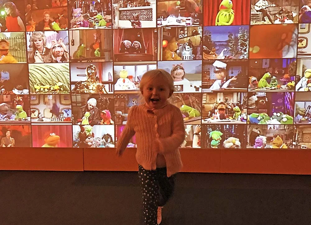 Rosie experiencing pure joy in front of the Muppet movie installation at The Museum of Pop Culture.