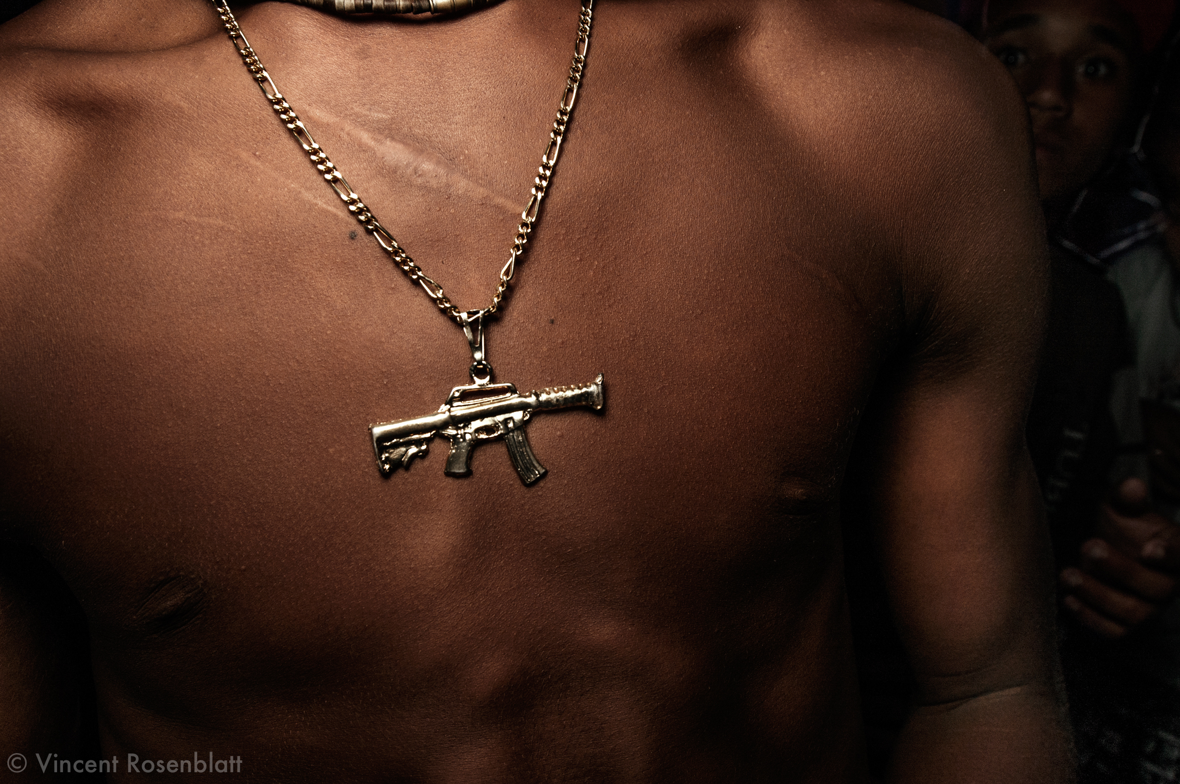  Submachine gun pendant ,  Baile of Curtisomrio soundsystem, downtown Rio de Janeiro.  A hint to the omnipresence of weapons on favelas' territory..The Funk carioca movement is fashion and look as well : the boys try and identify themselves to the ga