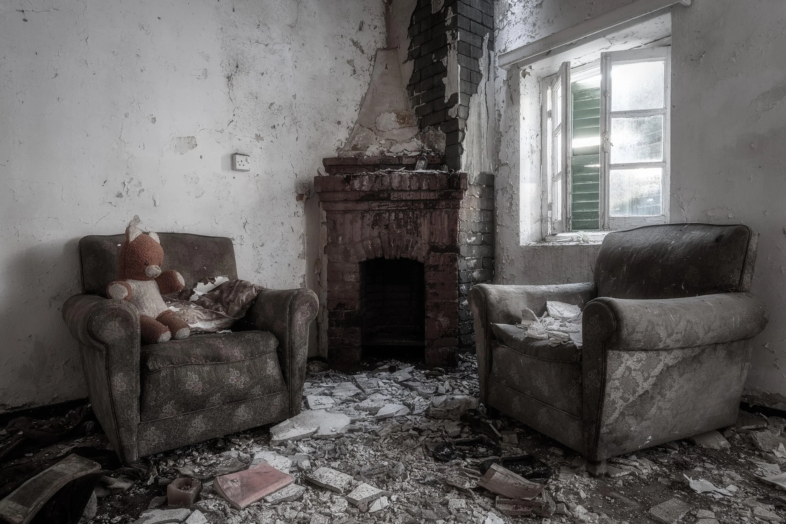 The Last Guest!


Two armchairs still face the fireplace,
as if someone had just stepped out of the room.

Dust has settled, the walls have cracked,
and silence has taken the place of voices.

Only the small teddy bear remains.

And yet, the light st
