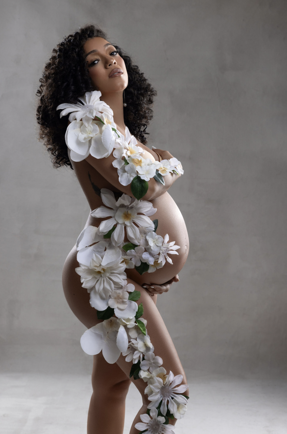 Floral body art maternity portrait with soft neutral tones and organic petal design.