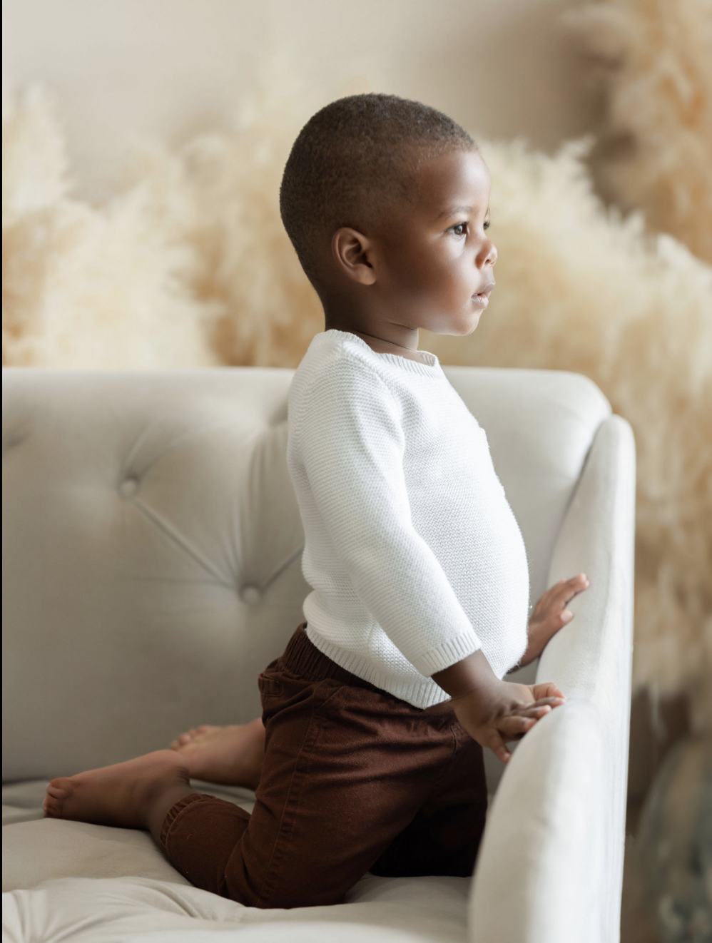 Studio portrait of a young child photographed with neutral tones and soft light in a timeless setting.
