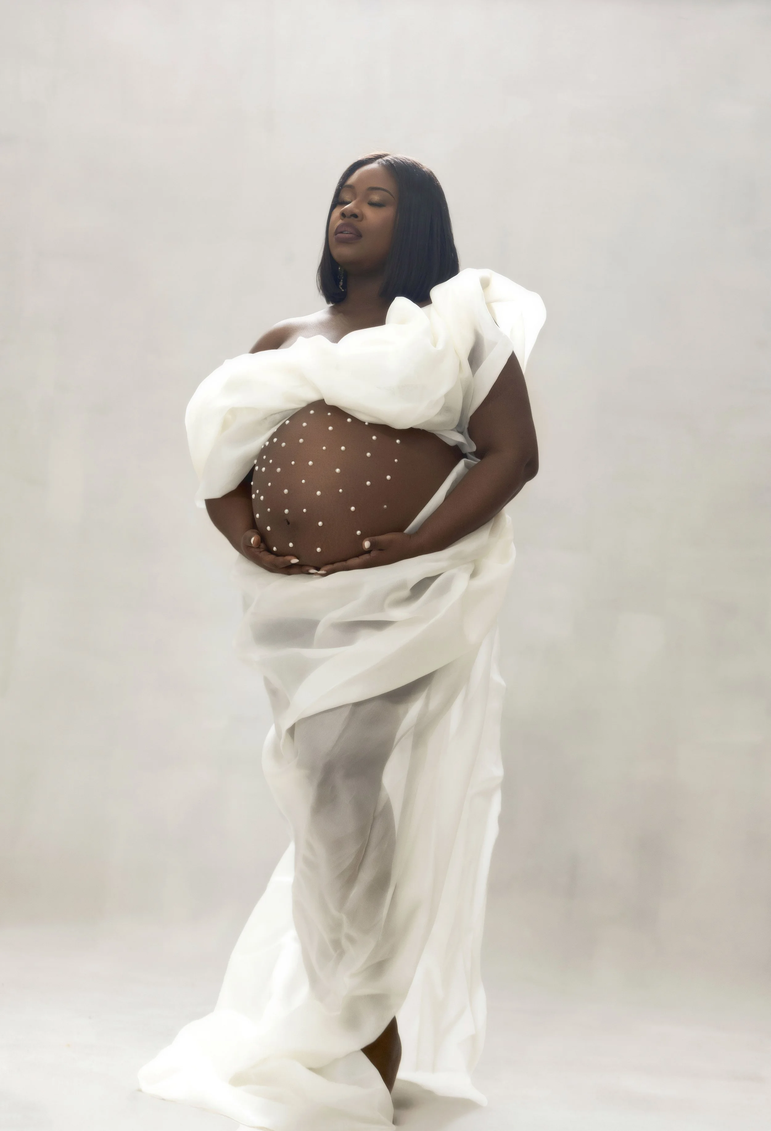 Silhouette maternity portrait of pregnant woman in white draped fabric, editorial luxury maternity photographer Brooklyn