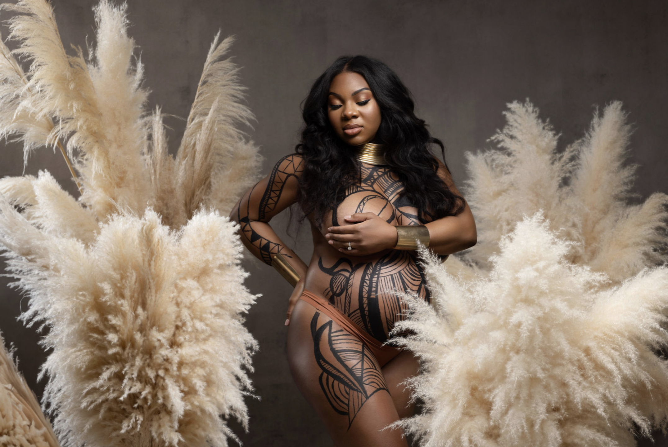 Maternity portrait with hand-painted body art, photographed in a fine art studio setting.