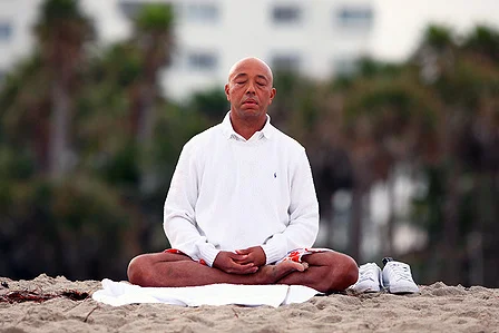 Russell Simmons meditating on the beach. Image via Success Story Nework.