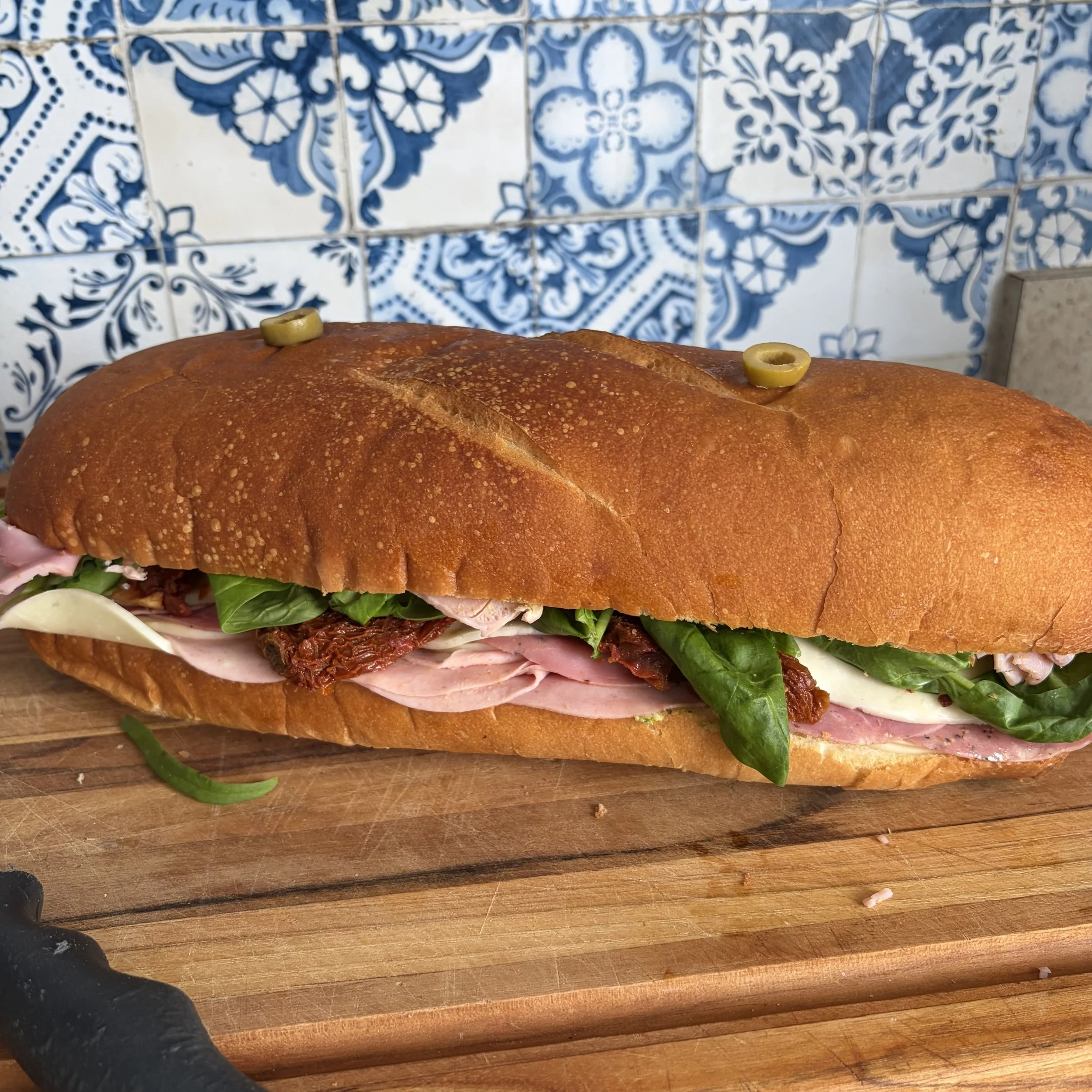 Grand sandwich italien entier dans un pain croûté garni de charcuteries, fromage et légumes
