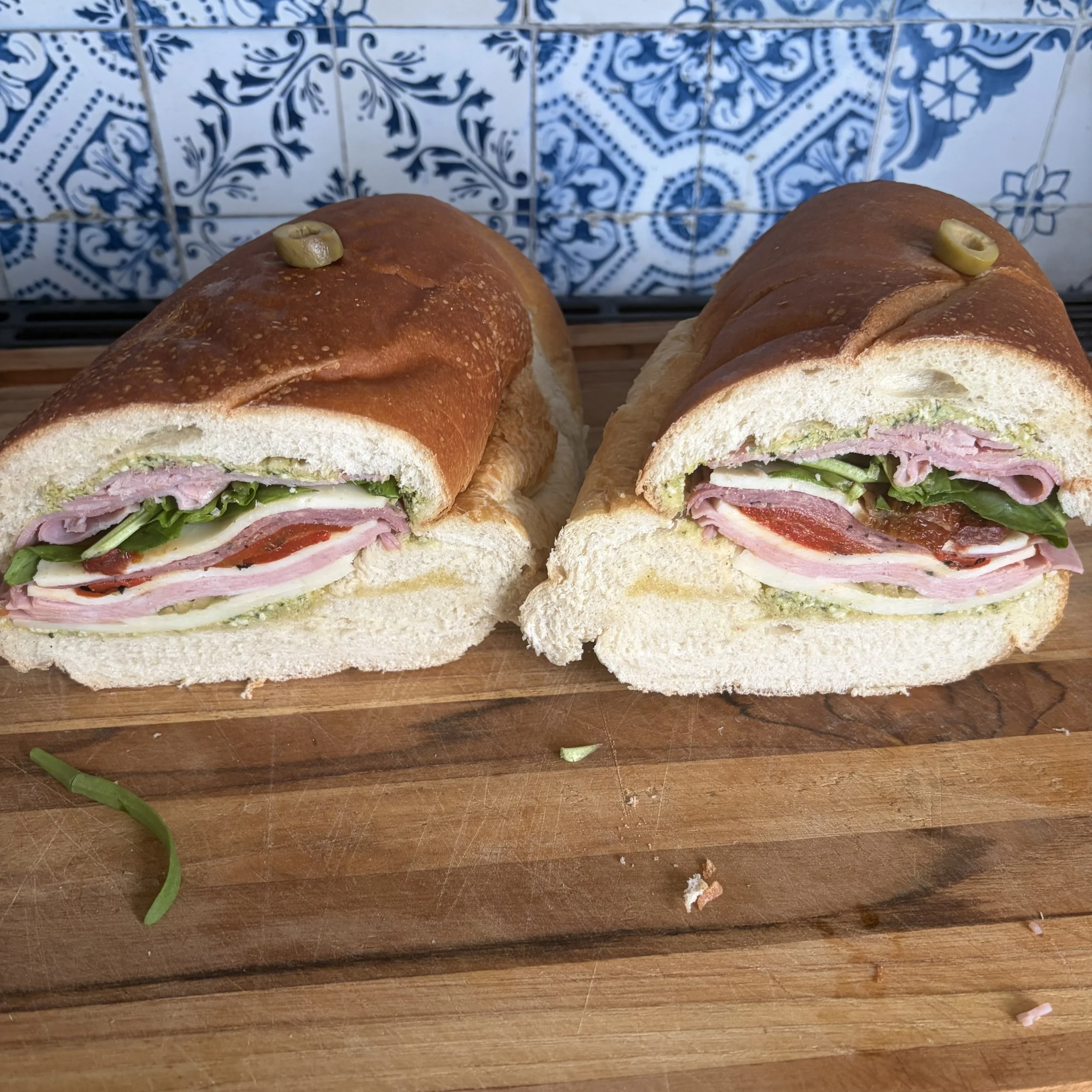 Sandwich italien pour la gang tranché en portions avec charcuteries, fromage et légumes dans un pain croûté
