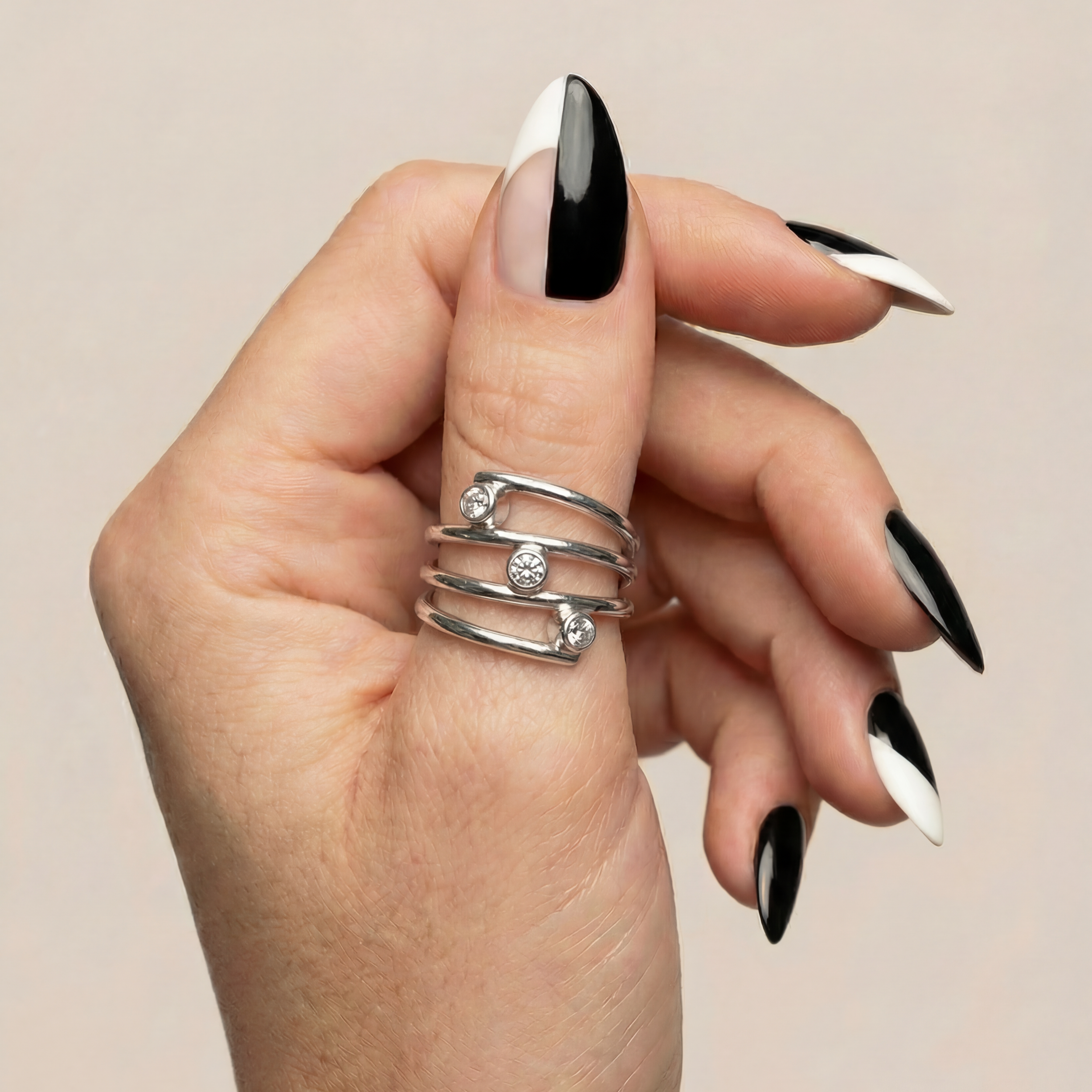 Hand model showcases silver spiral Trinity three stone diamond ring.