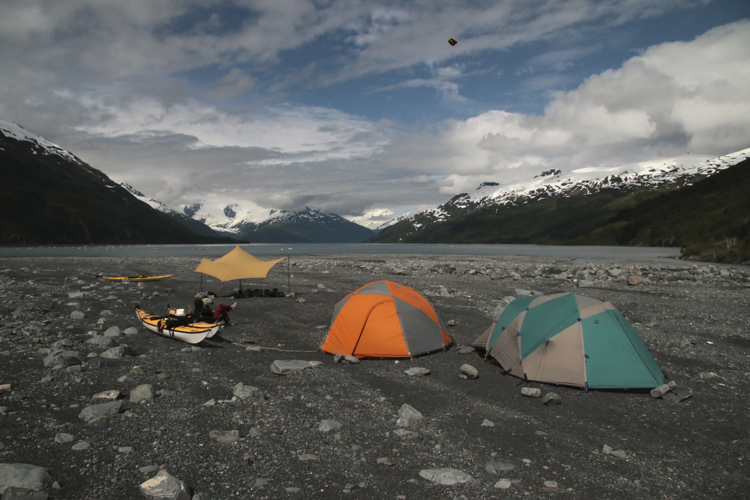 Once the weather cleared, the gravel field at the face of Harriman glacier was home for a few days. The tides are very high in the fjord so we parked our boats and made camp quite far from the water. Doubly smart since you never know when the glacier would calf, sending large waves your way. The winds off the glacier made for some cold camping (and bathing!), but also made for some great kite flying. Tied to a kayak, Pocket Kite stayed up all day. Here Barbara kicked back after a day of rangering.