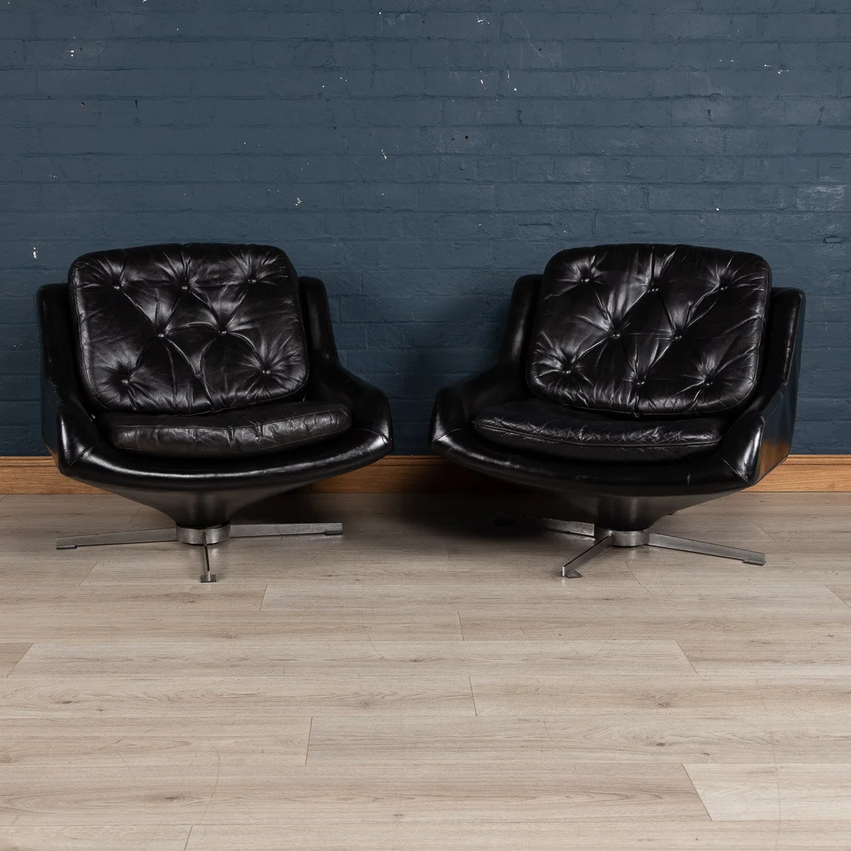 A pair of black leather lounge chairs, probably Italian, circa 1970