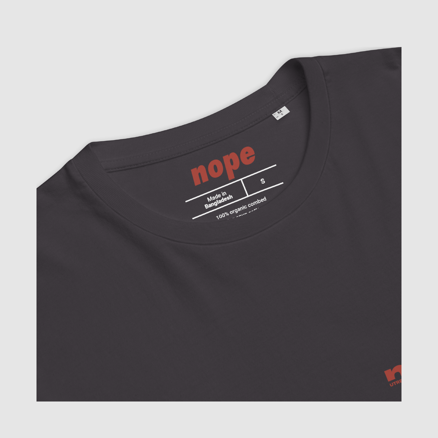 Close-up of anthracite Nope T-shirt neck label featuring red logo and ethical organic cotton info