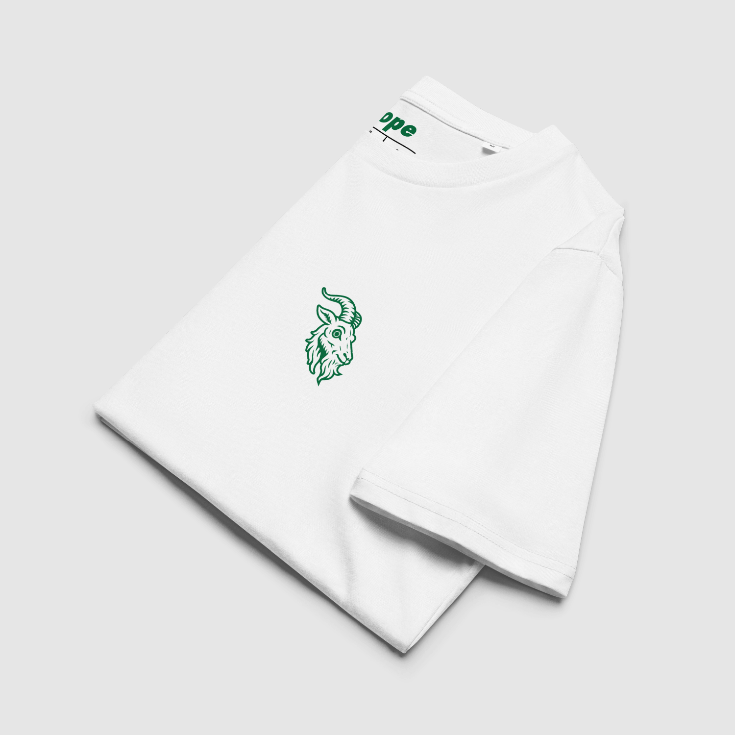 Folded white tee showing green Alpine goat chest graphic with visible internal branding.