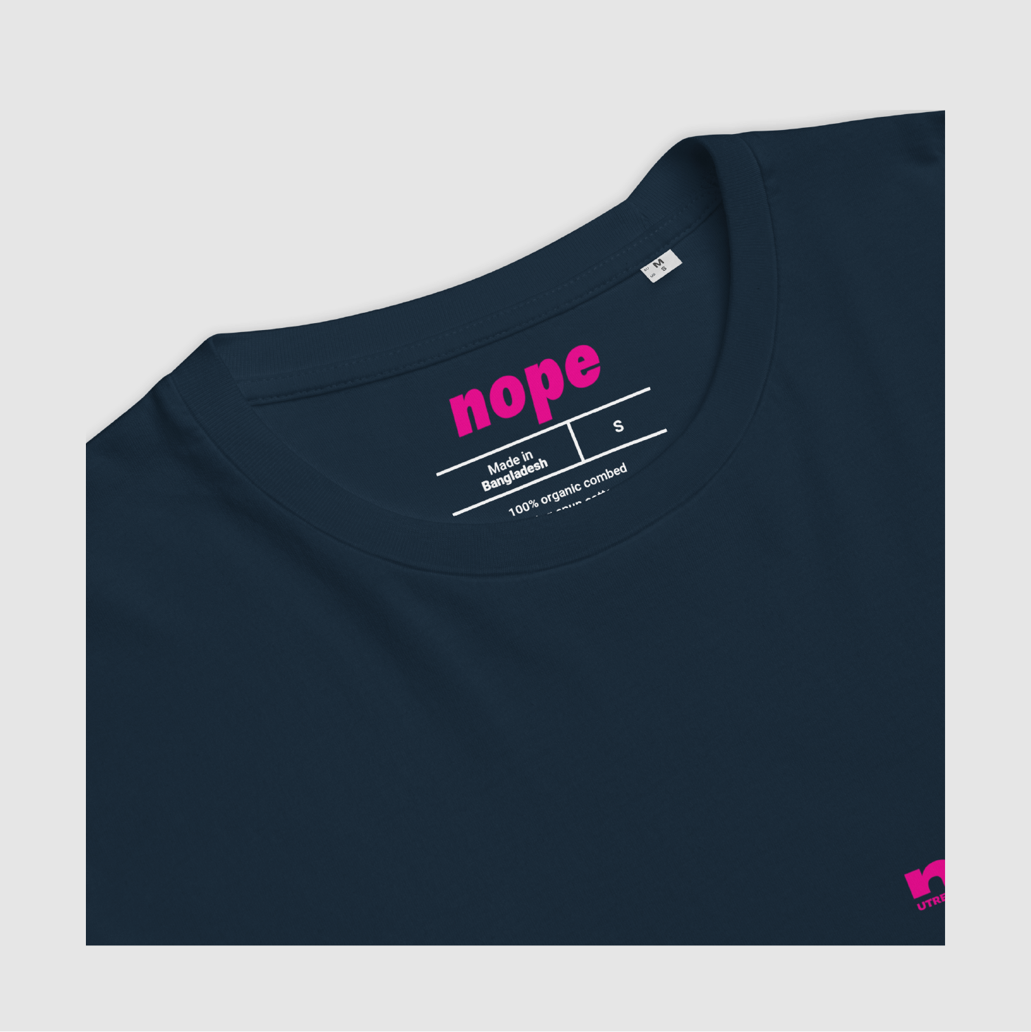 Close-up of navy Nope T-shirt inner neck label with pink logo and organic cotton info