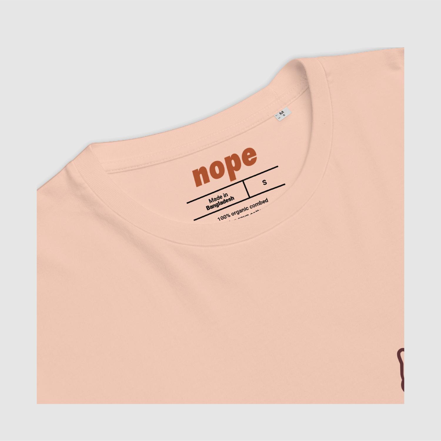 Neckline and inner label close-up – nope logo and size detail in orange