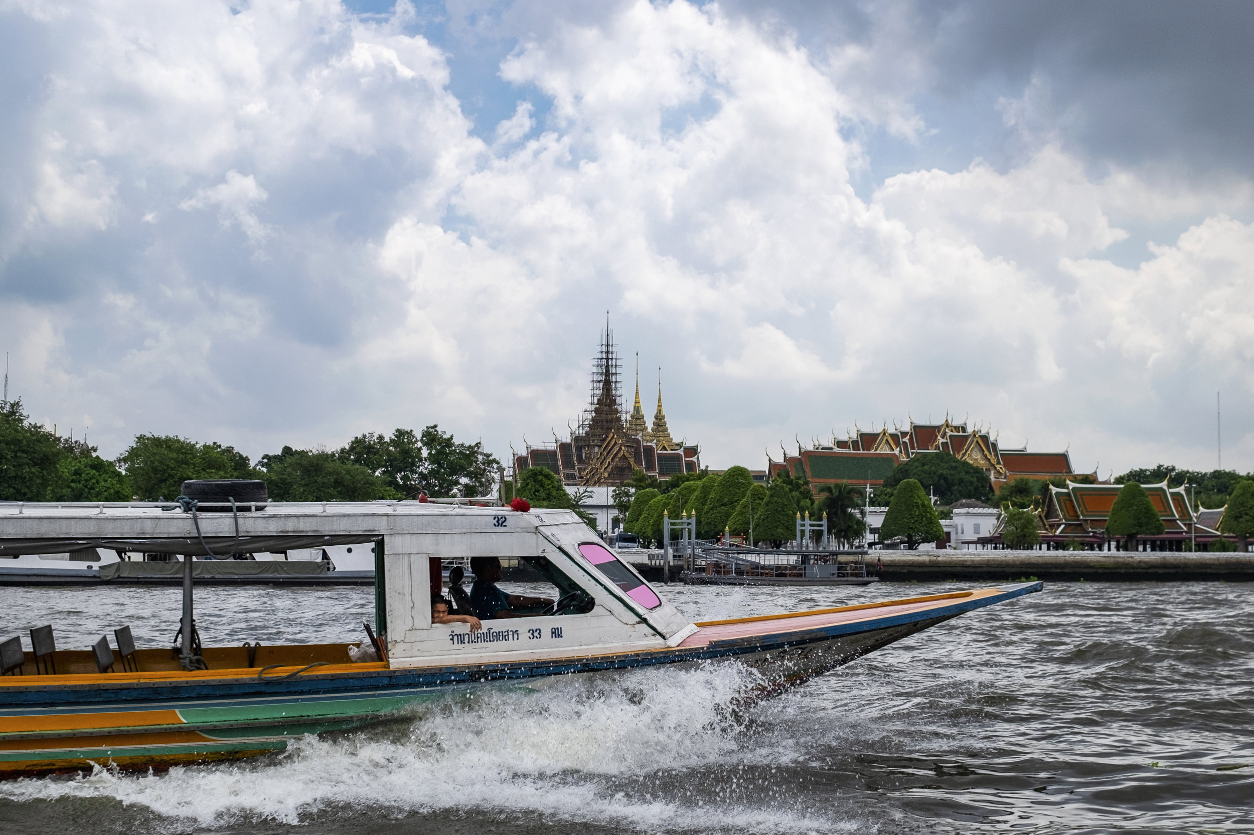  A man looks out of the cockpit of a long-tailed boat while traveling down the Chao Praya river in Bangkok, Thailand (Picture was taken from a river ferry) 