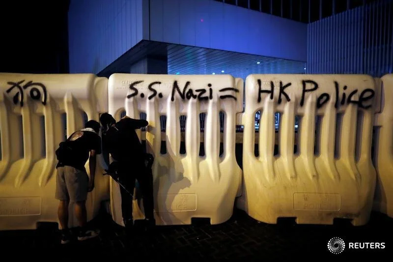  Anti-extradition bill protesters peep through road barriers in front of the government complex during the march to demand democracy and political reforms in Hong Kong, China, August 18, 2019. Picture taken on August 18, 2019. REUTERS/Kim Hong-Ji    