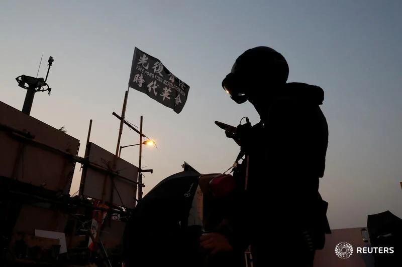  An anti-government protester looks his phone at a makeshift gate during a standoff with riot police at the Chinese University of Hong Kong, Hong Kong, China November 14, 2019. REUTERS/Tyrone Siu 