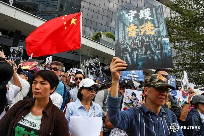  People hold a China national flag and signs as they participate in a pro-government rally to show their support for the police and government at the Legislative Council (LegCo) building in Hong Kong, China, November 16, 2019. REUTERS/Athit Perawongm