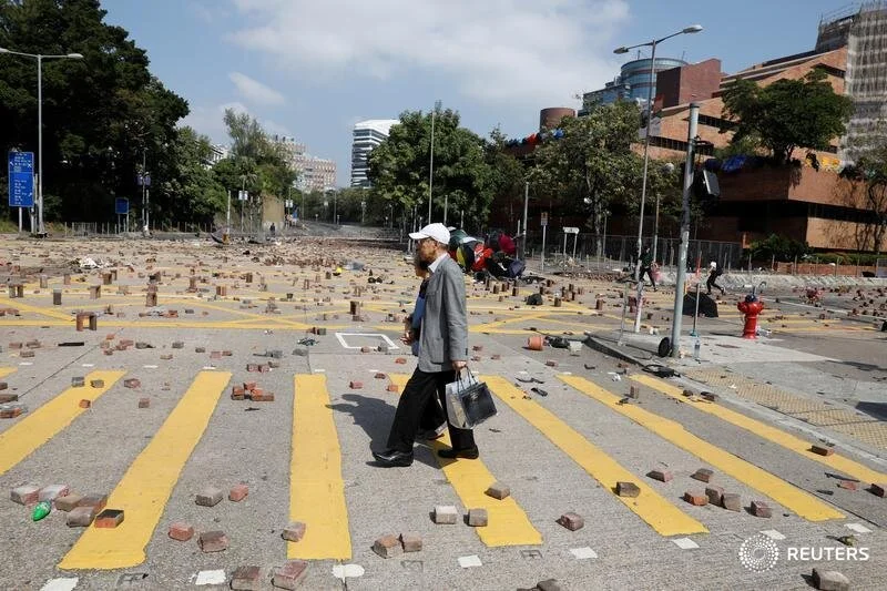  People cross a road scattered with bricks outside the Polytechnic University in Hong Kong, China, November 16, 2019. REUTERS/Adnan Abidi 
