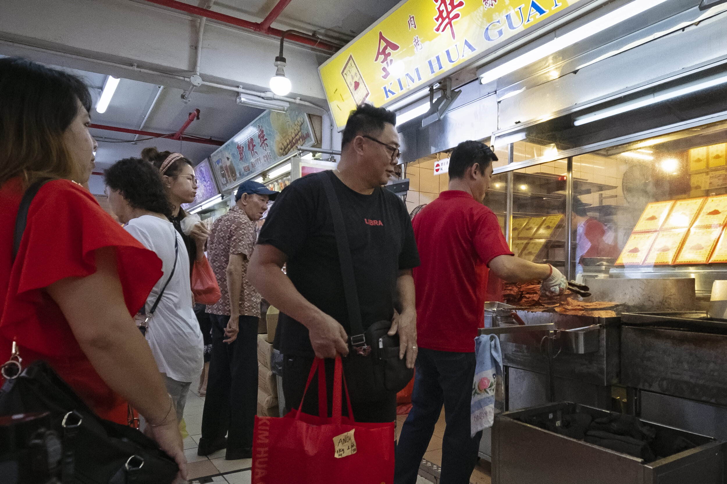  A customer (in black) leaves after collecting a pre-ordered bag of Bak Kwa while others wait for their turn 