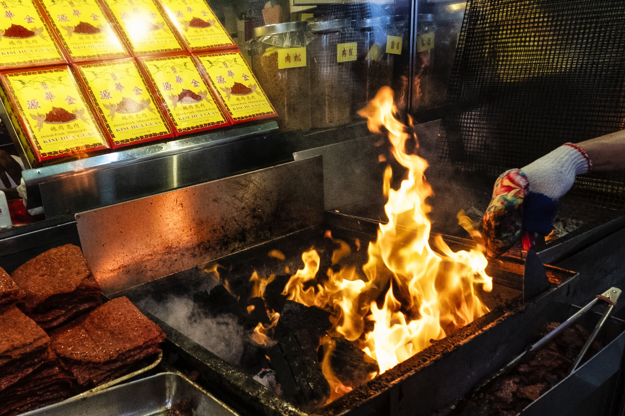  Flames rise as fresh pieces of charcoal are tossed into the grill as an employee prepares to cook the traditional Southern Chinese pork jerky, which is popular among Singaporean Chinese for Lunar New Year celebrations 