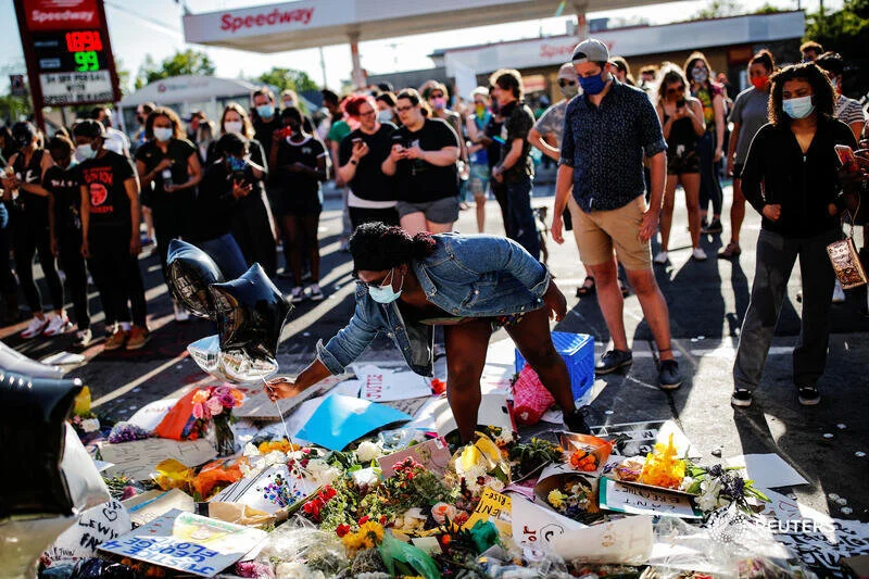  People gather around a makeshift memorial put up by protesters for African-American man George Floyd at the corner where he got arrested, in the aftermath of a white police officer getting caught on a bystander's video pressing his knee into Floyd's
