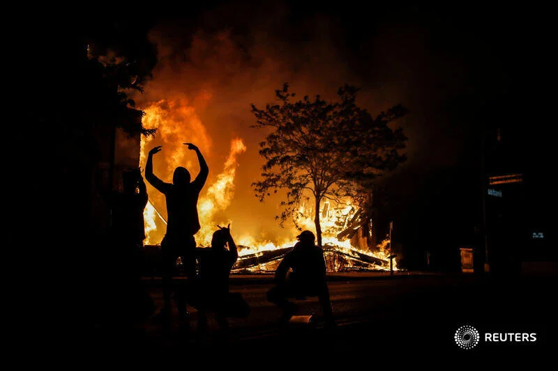  People react as fire rages in the background while protests continue after a white police officer was caught on a bystander's video pressing his knee into the neck of African-American man George Floyd, who later died at a hospital, in Minneapolis, M