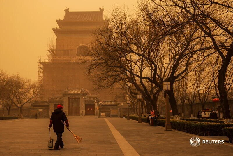  A person walks with a broom and dustpan during morning rush hour as Beijing, China, is hit by a sandstorm, March 15, 2021. REUTERS/Thomas Peter 