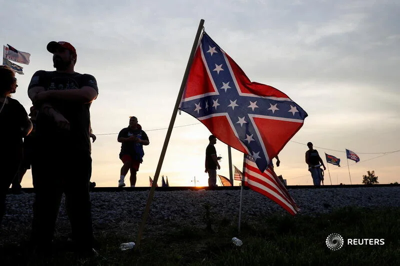  Supporters of former U.S. President Donald Trump stand near Confederate and U.S. flags as they gather for his first post-presidency campaign rally at the Lorain County Fairgrounds in Wellington, Ohio, U.S., June 26, 2021. REUTERS/Shannon Stapleton  
