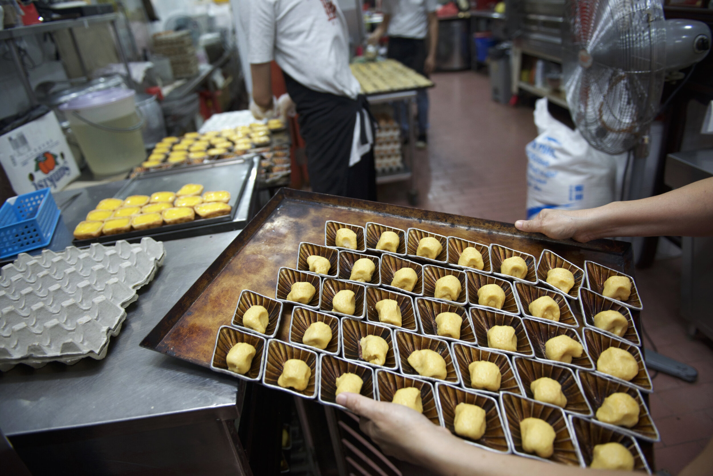  An employee carries a tray of dough in egg tart moulds before they are stretched into tart cases at traditional Cantonese confectionery Tong Heng in Singapore April 21, 2018. 