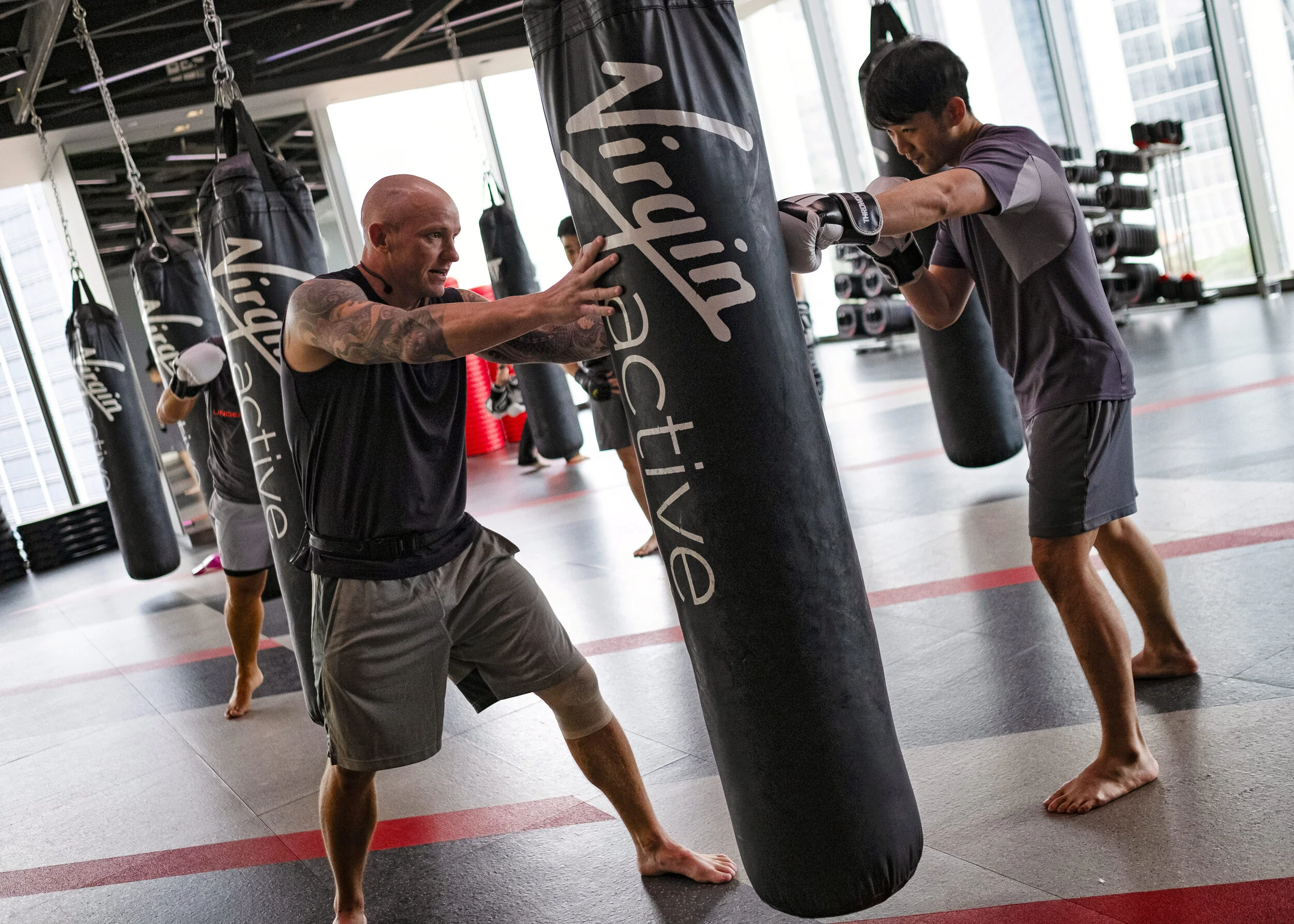  A trainer guides a gym member punching a sandbag at Virgin Active fitness club in central Singapore, March 5, 2019. (For Reuters) 