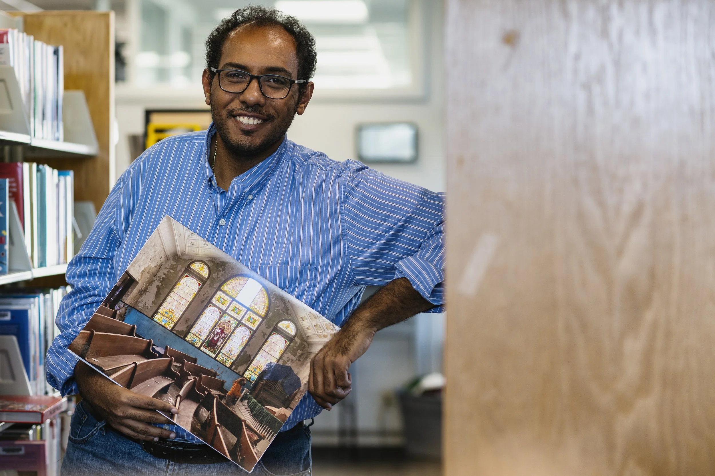  Photographer Ahmed Hamed, 36, of Cairo, Egypt, poses with one of his favorite images from his "Save Mount Zion Church" photo exhibition at The Plains Public Library in The Plains, Ohio, on Wednesday November 15, 2023. "Once I'm done with defending m