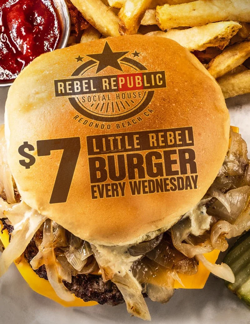 Close-up of the Little Rebel Burger with two beef patties, grilled onions, melted cheese, fries, ketchup in a cup, and pickles. Text: “$7 Little Rebel Burger Every Wednesday at Rebel Republic Social House.