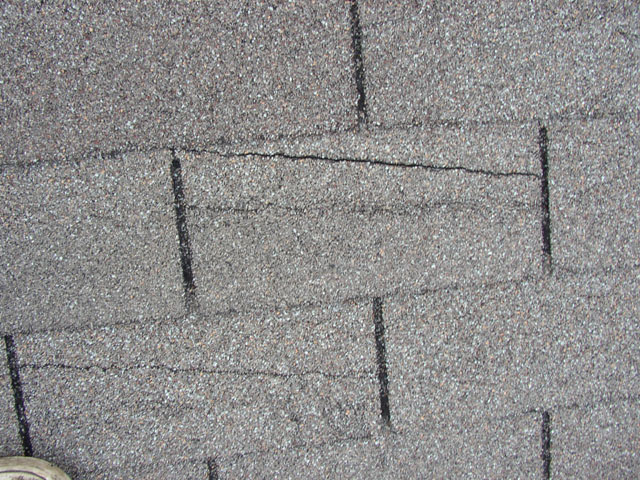 Sometimes wind damaged roofing shingles are harder to identify from the ground. As seen here, instead of missing tiles, the wind damage has manifested in the form of cracks. This is from high winds getting underneath the tiling, ripping them up from the adhesive, and folding them back onto themselves. This leaves both the tiling, the wood decking underneath and the interior of your home exposed to the elements. Other common signs of a wind damaged roofing include: Missing, Bruised, Dented, Cracked or Broken Tiles / Shingles. Granules collecting in gutters or downspouts. Leaks in your roof or ceiling. Dents on vents, gutters or flashing